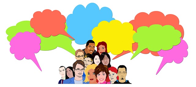 This cartoon-style image shows a group of about a dozen overlapping people, from the shoulders up. Arranged around them are colorful dialog balloons in the shape of clouds. The dialog balloons are empty.